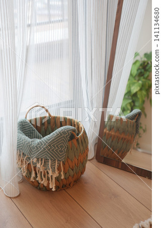 Basket near window with mirror and plant in indoor space Basket near window with mirror and plant in indoor space 141134680