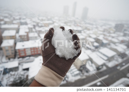 Hand holds snow in city during winter weather Hand holds snow in city during winter weather 141134701