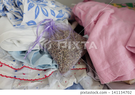 Lavender sachet among neatly folded clothes in a bedroom Lavender sachet among neatly folded clothes in a bedroom 141134702