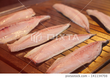 Fish fillets grilling on wooden grill during cooking time Fish fillets grilling on wooden grill during cooking time 141134708