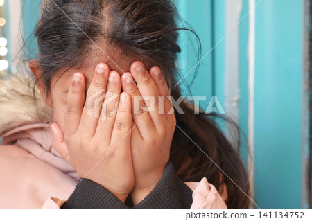 Girl covers her face in a moment of shyness or sadness 141134752