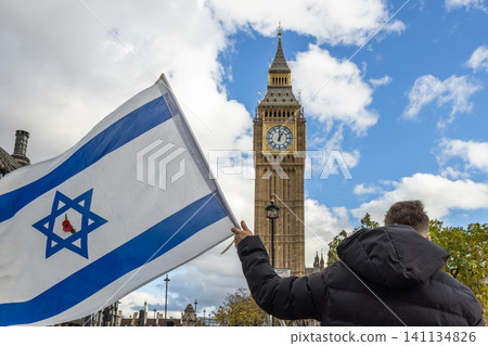Person holding an Israeli flag near Big Ben in London Person holding an Israeli flag near Big Ben in London 141134826