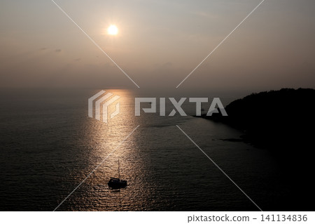 Sailboat Silhouette on Calm Sea at Golden Sunset with Island Sailboat Silhouette on Calm Sea at Golden Sunset with Island 141134836