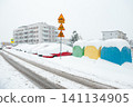 Snow covers cars and buildings during winter in a residential area with snowy streets in the early morning light 141134905