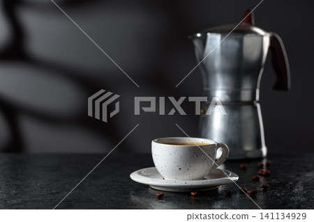 Cup of espresso and classic Italian aluminium moka pot on a stone table. Cup of espresso and classic Italian aluminium moka pot on a stone table. 141134929