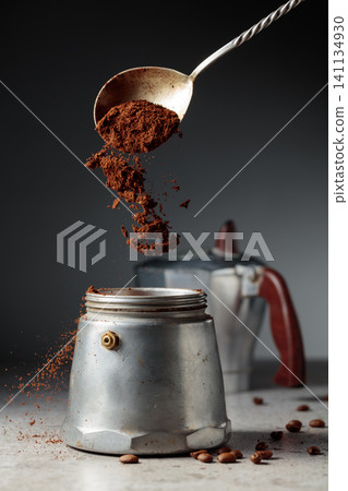 Grounded coffee is poured into a classic Italian aluminium moka pot, models from the 1950s to the 1960s. Grounded coffee is poured into a classic Italian aluminium moka pot, models from the 1950s to the 1960s. 141134930