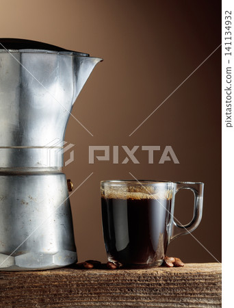 Cup of black coffee and classic Italian aluminium moka pot on an old wooden table. Cup of black coffee and classic Italian aluminium moka pot on an old wooden table. 141134932