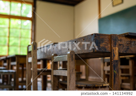 Glass windows, wooden chairs, and a blackboard in a classroom in an old wooden school building. Glass windows, wooden chairs, and a blackboard in a classroom in an old wooden school building. 141134992