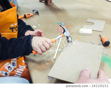 Parent helping child to hammer details of a wooden toy craft during Home Depot kids workshop - June 6, 2026 Federal Way WA, USA Parent helping child to hammer details of a wooden toy craft during Home Depot kids workshop - June 6, 2026 Federal Way WA, USA 141135211