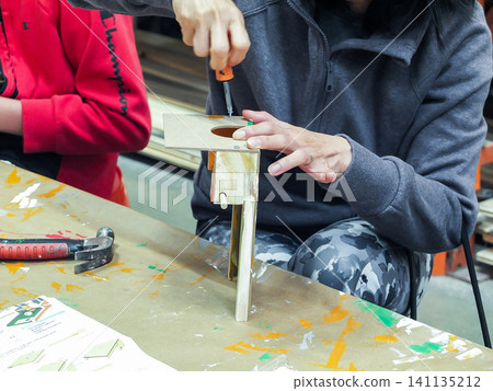 Parent helping child to hammer details of a wooden toy craft during Home Depot kids workshop - June 6, 2026 Federal Way WA, USA Parent helping child to hammer details of a wooden toy craft during Home Depot kids workshop - June 6, 2026 Federal Way WA, USA 141135212