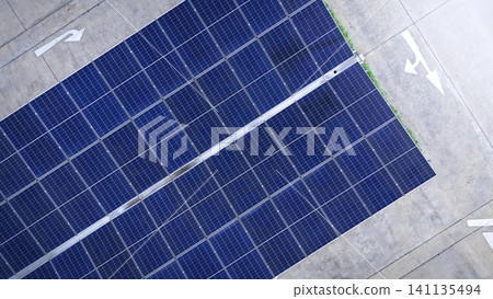 Solar roof. Aerial drone view of solar roof of carport or carpark. Photovoltaic panels covering a parking lot. Clean renewable energy infrastructure supports sustainable transportation. Solar energy Solar roof. Aerial drone view of solar roof of carport or carpark. Photovoltaic panels covering a parking lot. Clean renewable energy infrastructure supports sustainable transportation. Solar energy 141135494