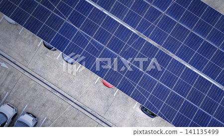Solar roof. Aerial drone view of solar roof of carport or carpark. Photovoltaic panels covering a parking lot. Clean renewable energy infrastructure supports sustainable transportation. Solar energy Solar roof. Aerial drone view of solar roof of carport or carpark. Photovoltaic panels covering a parking lot. Clean renewable energy infrastructure supports sustainable transportation. Solar energy 141135499