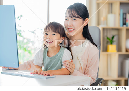 孩子在客廳和媽媽玩耍,媽媽則在一旁工作。 孩子在客廳和媽媽玩耍,媽媽則在一旁工作。 141136419
