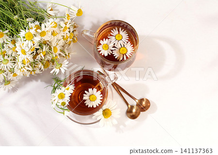 Chamomile iced tea in a transparent cup with natural small chamomile flowers on a light table, concept of herbal tea and proper natural nutrition, summer card and outdoor recreation, Chamomile iced tea in a transparent cup with natural small chamomile flowers on a light table, concept of herbal tea and proper natural nutrition, summer card and outdoor recreation, 141137363