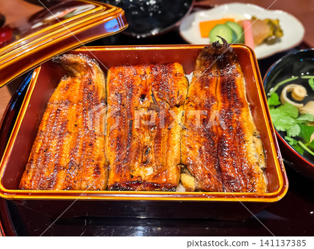 A close-up of a traditional, top-grade eel rice bowl, glistening with a secret sauce. A close-up of a traditional, top-grade eel rice bowl, glistening with a secret sauce. 141137385
