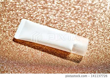 White cosmetic serum tube on golden glitter background White cosmetic serum tube on golden glitter background 141137726