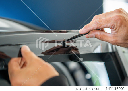 A car wrapping specialist applies a polyurethane film to the car. Detailer PPF A car wrapping specialist applies a polyurethane film to the car. Detailer PPF 141137901