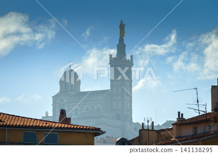 Basilique Notre-Dame de la Garde in the foggy background with red tiled roof Marseille houses Basilique Notre-Dame de la Garde in the foggy background with red tiled roof Marseille houses 141138295