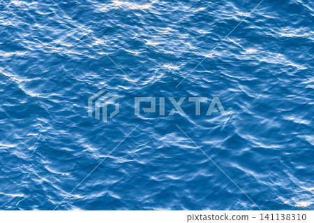 Glistening and shimmering blue ocean surface background with sun reflections Glistening and shimmering blue ocean surface background with sun reflections 141138310