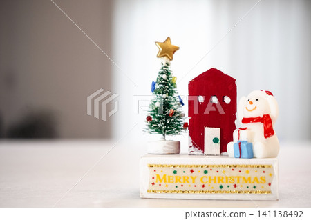 A cute snowman, a red house, and a Christmas tree ornament alongside the words "Merry Christmas." A cute snowman, a red house, and a Christmas tree ornament alongside the words "Merry Christmas." 141138492