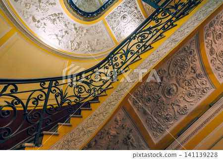 Naples, Italy - November 5, 2018, Panoramic view of antique curved staircase decorated with stucco with wrought iron railings with a floral pattern at Galleria Umberto I, without people, Naples, Italy Naples, Italy - November 5, 2018, Panoramic view of antique curved staircase decorated with stucco with wrought iron railings with a floral pattern at Galleria Umberto I, without people, Naples, Italy 141139228
