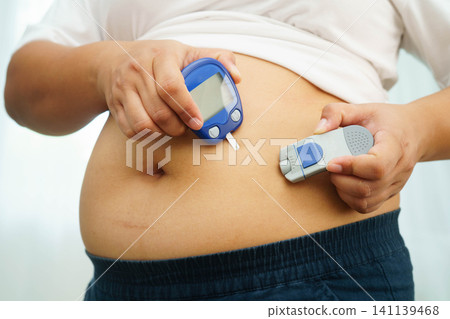 Asian woman injecting herself diabetes injecting insulin in stomach at home. Asian woman injecting herself diabetes injecting insulin in stomach at home. 141139468