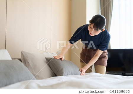 一位清潔阿姨正在整理客房的床鋪。 141139695
