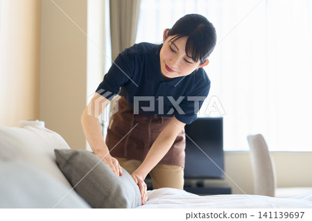 A cleaning lady making the beds in the guest rooms. A cleaning lady making the beds in the guest rooms. 141139697