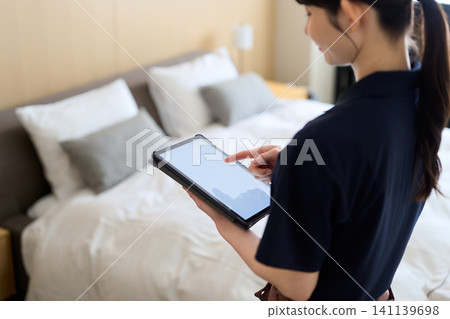 A cleaning lady manages her work using a tablet. A cleaning lady manages her work using a tablet. 141139698