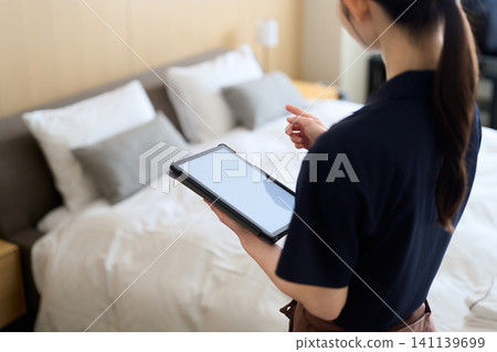 A cleaning lady manages her work using a tablet. A cleaning lady manages her work using a tablet. 141139699