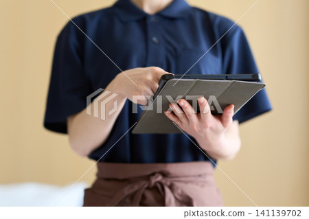 A cleaning lady manages her work using a tablet. A cleaning lady manages her work using a tablet. 141139702