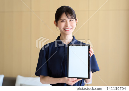 A cleaning lady shows the screen of her tablet. A cleaning lady shows the screen of her tablet. 141139704