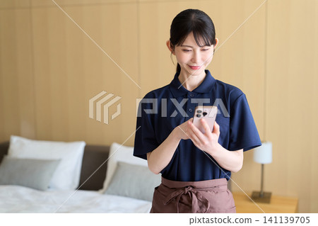A cleaning worker who manages her work using her smartphone A cleaning worker who manages her work using her smartphone 141139705
