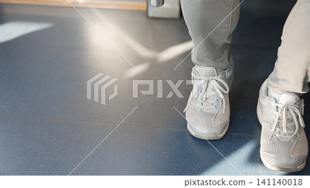 The feet and sneakers of commuters standing inside the train The feet and sneakers of commuters standing inside the train 141140018