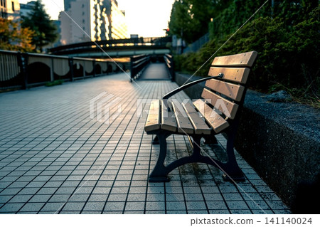 An empty bench standing by the river at dusk. An empty bench standing by the river at dusk. 141140024