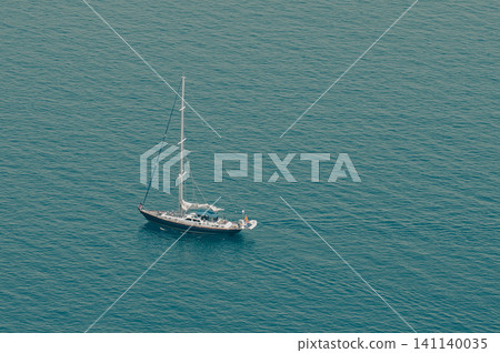 A bird's-eye view of a yacht floating on the deep blue sea. A bird's-eye view of a yacht floating on the deep blue sea. 141140035