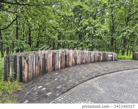 A garden in a green forest with curved railway sleeper walls and cobblestone paths. A garden in a green forest with curved railway sleeper walls and cobblestone paths. 141140327