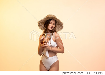 Woman wearing straw hat and white bikini enjoying a refreshing drink during summer vacation leisure Woman wearing straw hat and white bikini enjoying a refreshing drink during summer vacation leisure 141141498