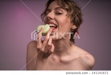 Young woman enjoying sweet green macaron, savoring dessert with happy expression and open mouth Young woman enjoying sweet green macaron, savoring dessert with happy expression and open mouth 141141671