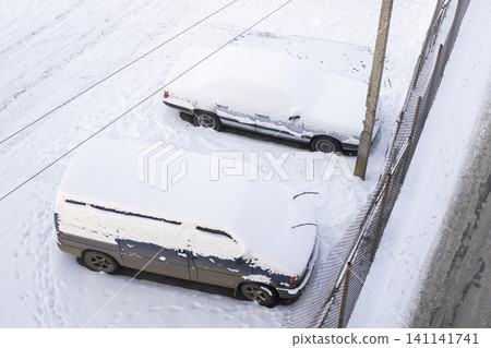Cars and van covered in fresh snow during winter, parking lot view from above, cold season concept Cars and van covered in fresh snow during winter, parking lot view from above, cold season concept 141141741