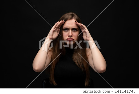 Woman feeling stressed, having a headache, and showing signs of frustration and emotional upset on a black background Woman feeling stressed, having a headache, and showing signs of frustration and emotional upset on a black background 141141743