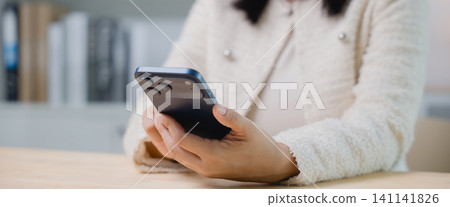 Businesswoman using mobile phone and smartphone technology online at office desk, close up of female hands holding modern device for business communication and digital connection on table Businesswoman using mobile phone and smartphone technology online at office desk, close up of female hands holding modern device for business communication and digital connection on table 141141826