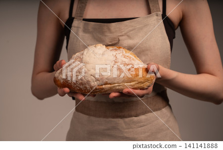 Baker holding fresh artisan bread loaf, showcasing handmade baking, flour, and natural ingredients Baker holding fresh artisan bread loaf, showcasing handmade baking, flour, and natural ingredients 141141888