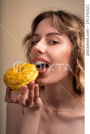 Young woman enjoying sweet yellow donut, a tasty dessert for snacking and craving satisfaction Young woman enjoying sweet yellow donut, a tasty dessert for snacking and craving satisfaction 141142021