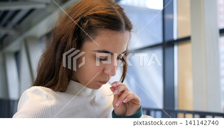 Woman near railing testing lollipop with curious expression, subtle inhale of sweet scent, close framing highlights nose and lips, soft ambient transit lighting creating gentle contrast. Woman near railing testing lollipop with curious expression, subtle inhale of sweet scent, close framing highlights nose and lips, soft ambient transit lighting creating gentle contrast. 141142740