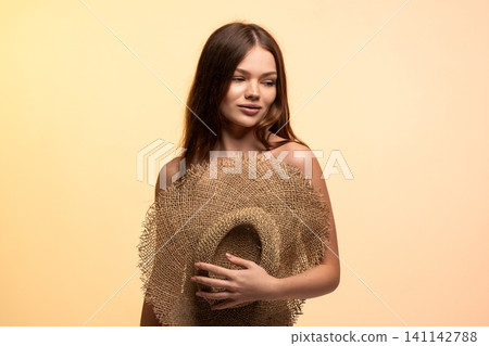Young woman holding straw hat, symbolizing summer holiday, vacation, and natural beauty on light background Young woman holding straw hat, symbolizing summer holiday, vacation, and natural beauty on light background 141142788