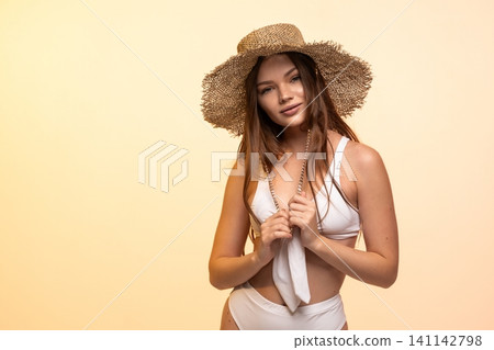 Young woman posing in a studio, wearing a straw hat and white swimsuit, perfect for summer, vacation, and fashion concepts Young woman posing in a studio, wearing a straw hat and white swimsuit, perfect for summer, vacation, and fashion concepts 141142798