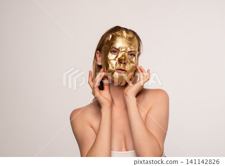 Woman applying gold leaf facial mask for luxury skincare beauty treatment, anti-aging, and hydration Woman applying gold leaf facial mask for luxury skincare beauty treatment, anti-aging, and hydration 141142826