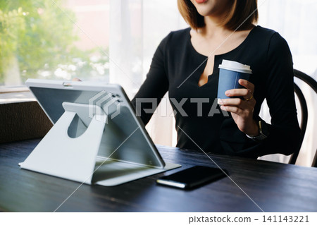 Confident businesswoman working on laptop, tablet and smartphone at her workplace 141143221