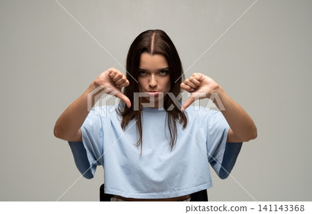 Woman showing thumbs down gesture expressing strong dislike, disapproval, rejection, and negative feedback Woman showing thumbs down gesture expressing strong dislike, disapproval, rejection, and negative feedback 141143368